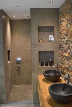 a bathroom with stone walls and two black bowls on the counter next to each other