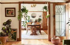 a living room filled with lots of plants next to a dining room table and chairs