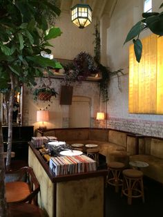 the interior of a restaurant with tables and stools next to a tree in front of it