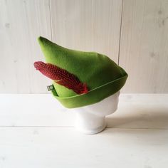 a green hat with a red flower on it