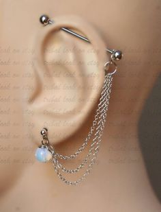 a pair of ear piercings with chains and beads on top of a mannequin's head