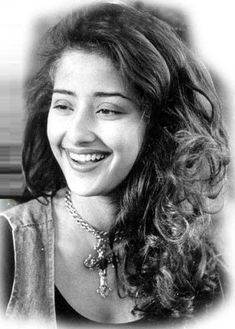 a black and white photo of a woman with long curly hair smiling at the camera