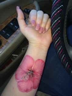 a woman's arm with a pink flower on the left side of her wrist