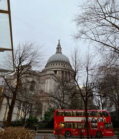 a red double decker bus parked in front of a building with a dome on top