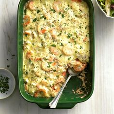 a green casserole dish filled with shrimp and cheese