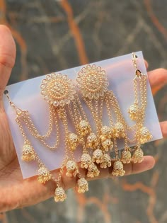 three pairs of gold - plated chandelier earrings are displayed in front of a card