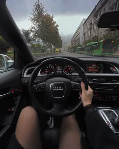 a person driving a car on a city street with other cars in the back ground