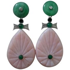 In these classic Art Deco Style earrings we have the tops with 2 Jade discs with small diamonds set in gold in the center ,the middle parts are composed of 2 elements in White Gold, Diamonds small round Emerald cabs and Black Enamel,while in the bottom parts we have 2 engraved Pink opal flat drops measuring 25 x 35 mm. In 1978 our workshop started in Italy to make simple-chic Art Deco style jewellery, completely handmade and using the typical gemstones of that period (1920-1930 circa) : genuine Jades, Turquoise , Lapis Lazuli and other color gemstones set in white Gold, Diamonds and Enamels. We always put particular attention on the details of the antique jewels,like "Milgrain" setting and light use of gold, so our pieces are affordable, easy and comfortable to wear. Today we also offer ou Gold Diamond Drop Earrings, Emerald Diamond Earrings, Opal Drop Earrings, Chic Art, Middle Parts, Simple Chic, Estilo Art Deco