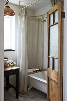 a white bath tub sitting under a window next to a wooden door in a bathroom