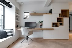 a modern home office with white walls and wood flooring, built in shelving units