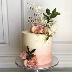 a white and pink cake sitting on top of a metal stand with flowers in it