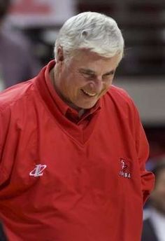 an older man in a red shirt is walking on the court with his head down