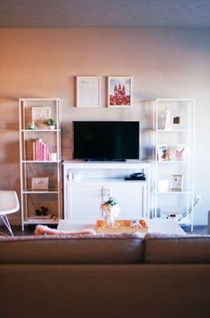 a living room filled with furniture and a flat screen tv on top of a wooden shelf