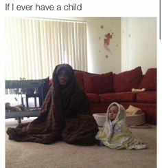 a woman sitting on the floor next to a child wearing a blanket and holding a laptop