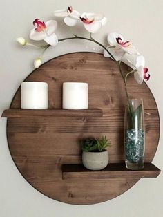 a wooden shelf with candles and flowers on it next to a wall mounted candle holder