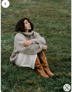 a woman sitting in the grass with her arms crossed