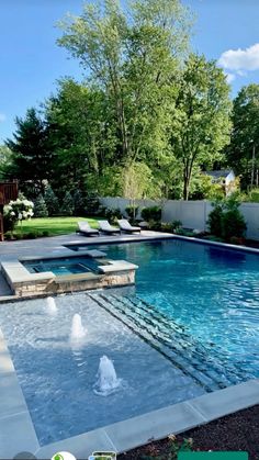 an outdoor swimming pool in the middle of a yard with lounge chairs and trees around it