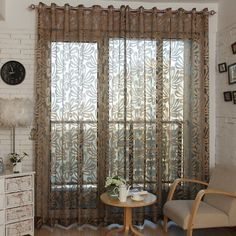 a living room with white brick walls and curtains, two chairs in front of the window