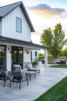 an outdoor patio with chairs and tables next to a white house in the evening sun