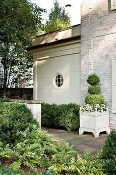 a brick house with white shutters and potted plants