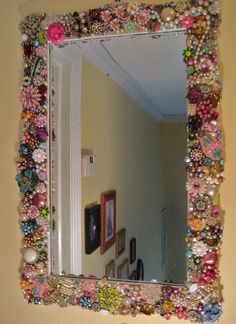 there is a mirror made out of beads and other things on the wall above it