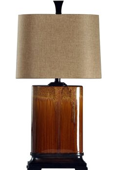 a brown table lamp with a beige shade on the base and a black wooden cabinet underneath it