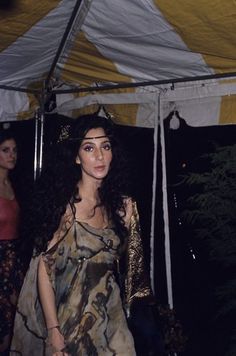 a woman in a dress standing under a tent