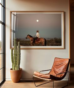 a man riding on the back of a brown horse next to a cactus in a living room