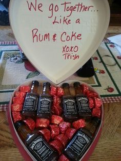 a heart shaped box filled with lots of chocolates next to a sign that says we go together like a rum & coke xoxo