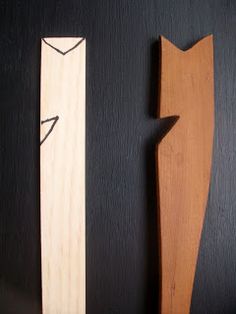 two wooden objects are sitting next to each other on a black surface and one is shaped like a cat