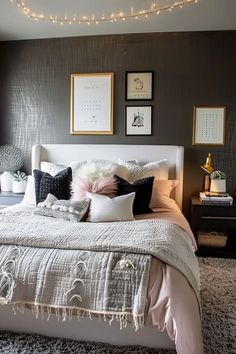 a white bed topped with lots of pillows next to a wall covered in framed pictures