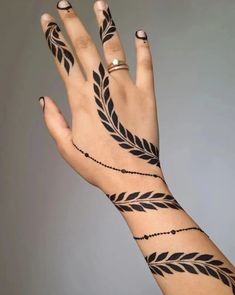 a woman's hand with black tattoos on it and a ring in the middle