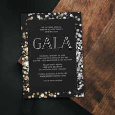 a black and gold wedding card with the word galaa on it, surrounded by confetti