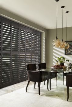 a dining room table and chairs with blinds on the wall