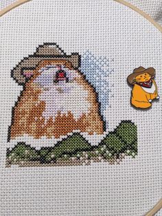 a cross stitch picture with a cat wearing a cowboy hat