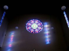 a large stained glass window in the center of a room with several lights on it