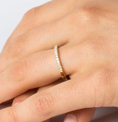 a woman's hand with a diamond ring on her left hand, wearing a yellow gold band