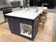 a kitchen with an island and stools on the floor in front of two sinks