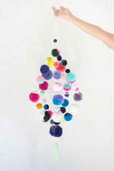 a person is holding up a mobile with pom - poms hanging from it