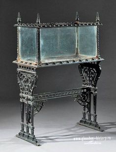 an ornate metal table with glass shelves on the top and bottom, sitting in front of a black background