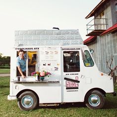 an ice cream truck parked in front of a building with a woman standing at the window