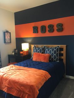 a bedroom with orange and blue bedding, black walls and a clock on the wall