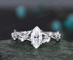 a white gold engagement ring with an oval cut diamond in the center and leaves around it