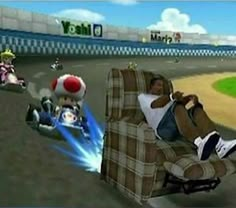 a man sitting in a recliner on top of a video game screen with mario kart racing