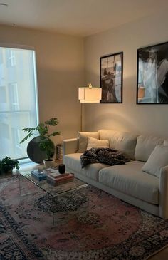 a living room filled with furniture next to a large window and a painting on the wall