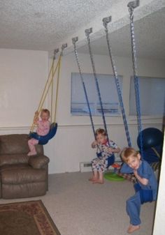 three children playing on swings in a living room