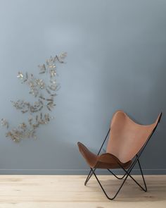 a chair sitting on top of a hard wood floor in front of a wall with flowers