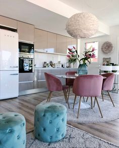 a dining room table with pink chairs and blue stools