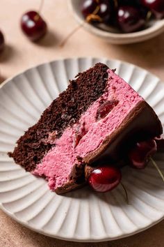 a piece of cake on a plate with cherries