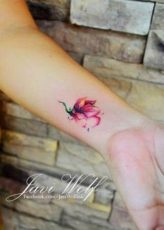 a small pink flower tattoo on the wrist